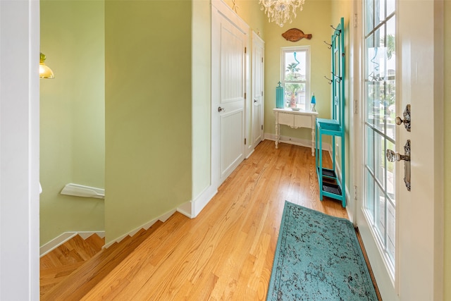 hall with baseboards, a chandelier, and wood finished floors