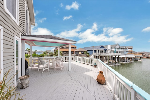 wooden terrace with a residential view, a water view, and outdoor dining space