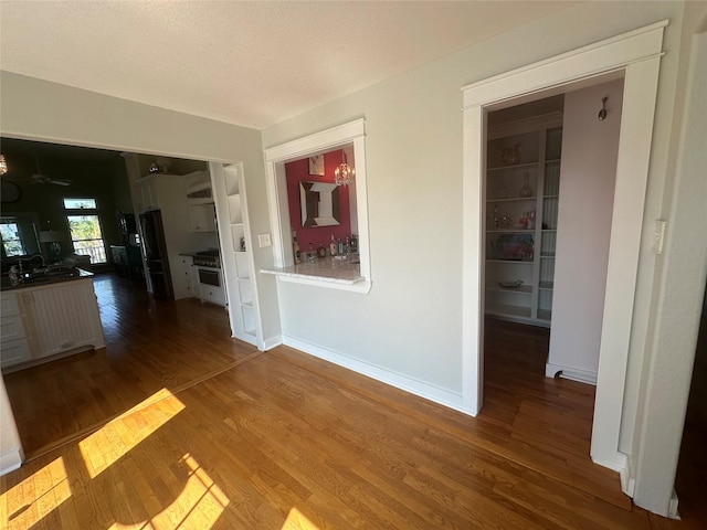 hall with a sink, baseboards, and wood finished floors