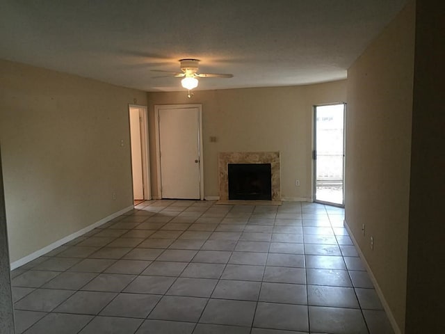 unfurnished living room with ceiling fan, light tile floors, and a fireplace