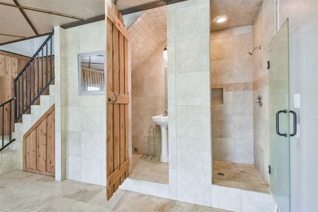 bathroom with a shower with shower door, tile patterned flooring, and tile walls