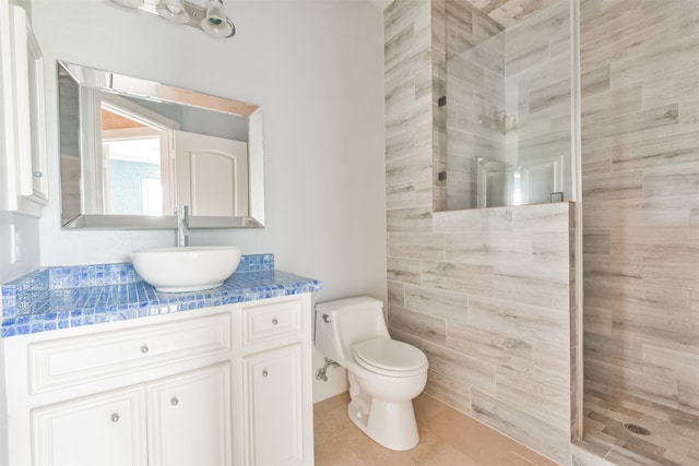 bathroom with vanity, a tile shower, tile patterned flooring, and toilet