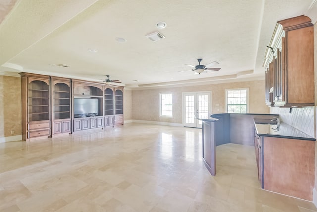 kitchen featuring ceiling fan, a raised ceiling, backsplash, and light tile patterned floors