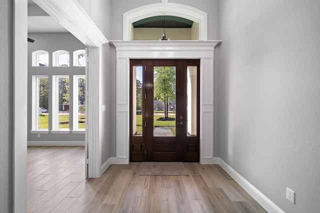 foyer with light hardwood / wood-style flooring and a towering ceiling