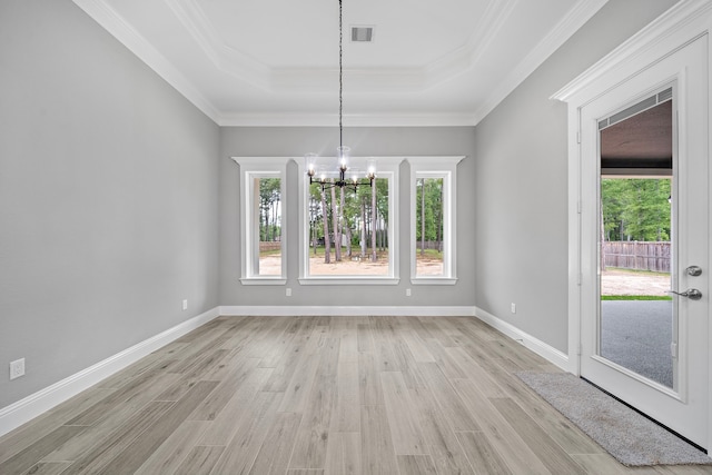 unfurnished dining area with an inviting chandelier, a raised ceiling, crown molding, and light hardwood / wood-style floors