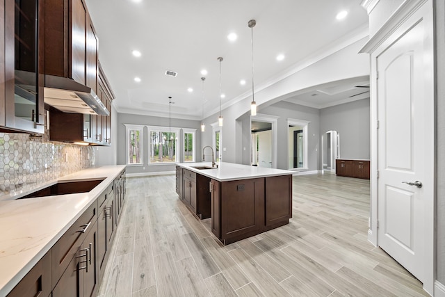 kitchen featuring sink, backsplash, pendant lighting, a kitchen island with sink, and black electric stovetop