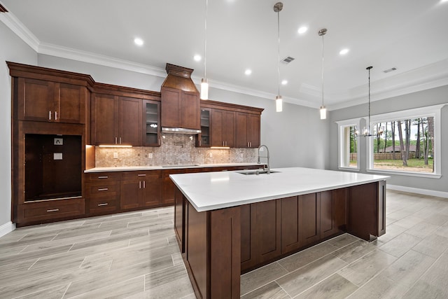 kitchen with black electric stovetop, sink, pendant lighting, a center island with sink, and a chandelier