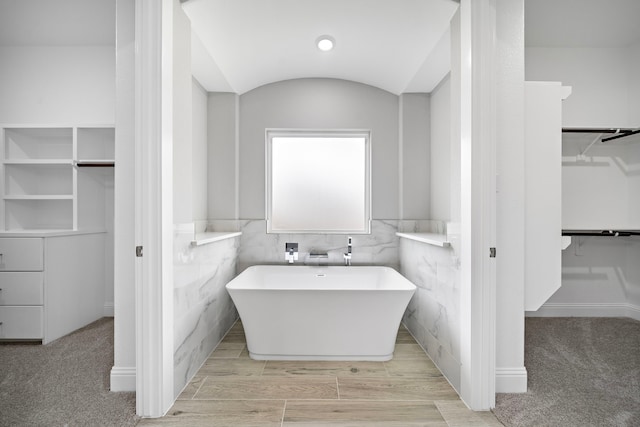 bathroom featuring vaulted ceiling and a bathtub