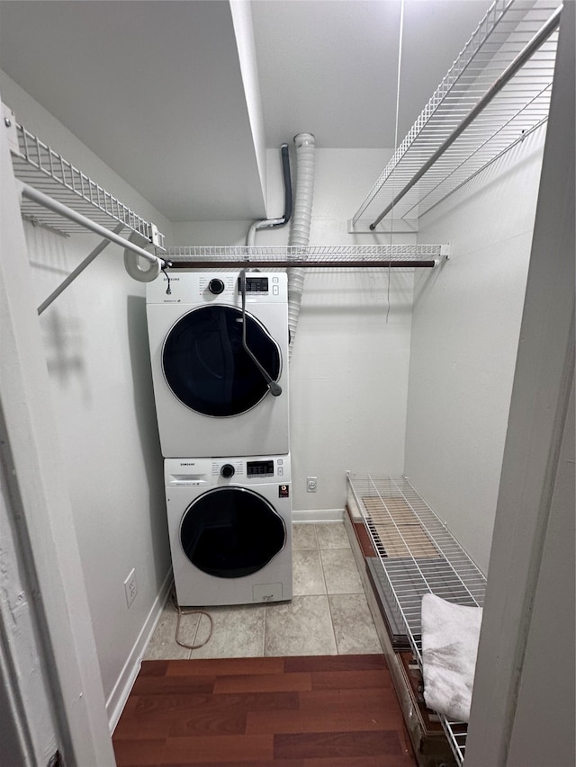 laundry area with stacked washer / drying machine and light tile floors