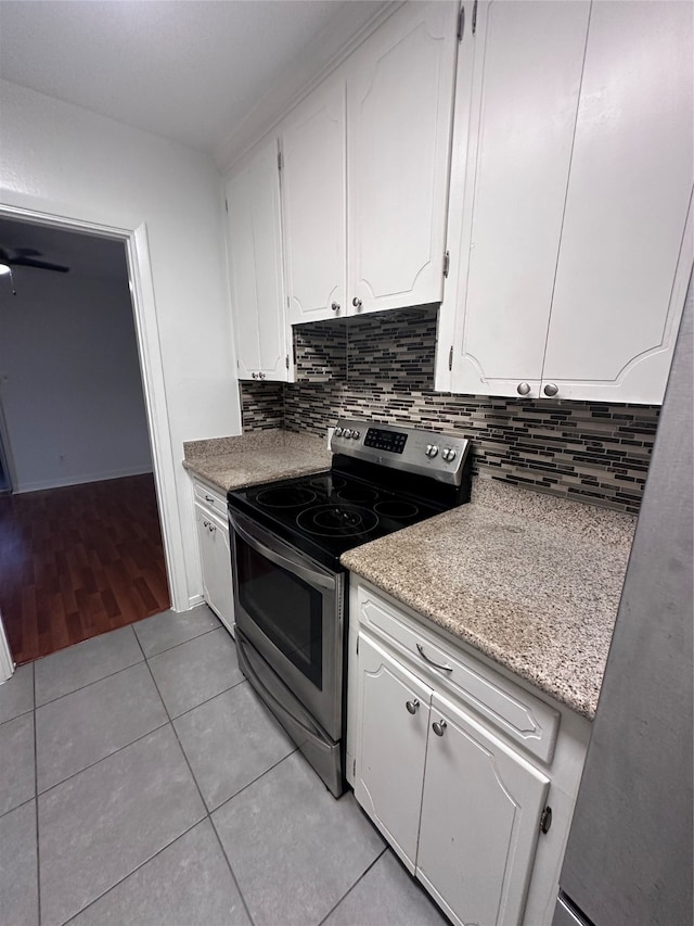 kitchen featuring white cabinets, backsplash, light wood-type flooring, and electric stove