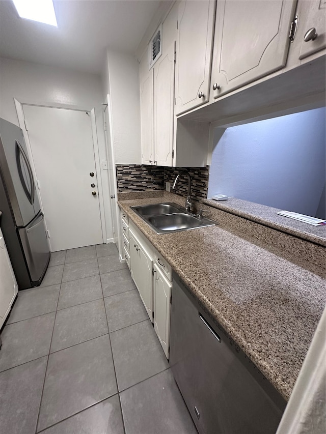 kitchen featuring light tile floors, white cabinets, sink, stainless steel refrigerator, and tasteful backsplash