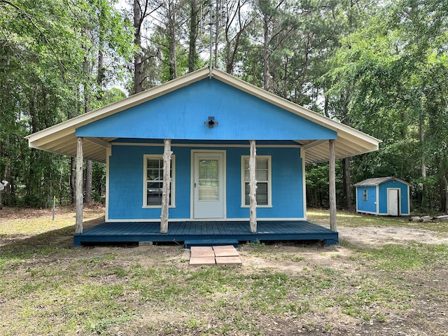 bungalow featuring a porch and a shed