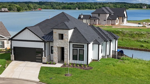 view of front facade featuring a garage, a water view, and a front lawn