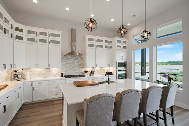 kitchen with wall chimney exhaust hood, stainless steel oven, dark wood-type flooring, and a sink