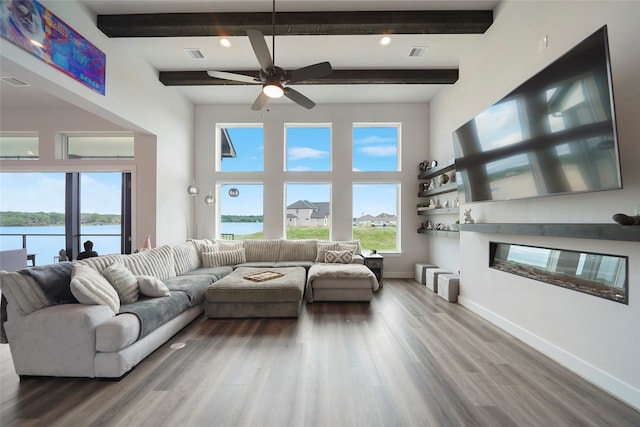 living area with baseboards, visible vents, wood finished floors, a water view, and beam ceiling