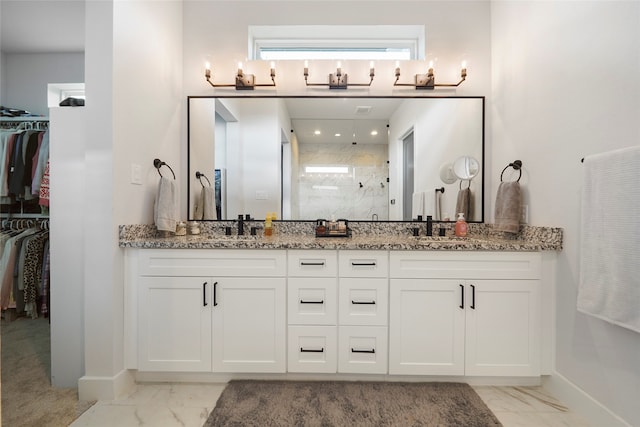 bathroom with a stall shower, marble finish floor, a spacious closet, and double vanity