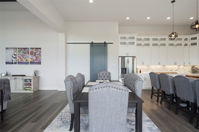 dining room with a barn door, dark wood-type flooring, and recessed lighting