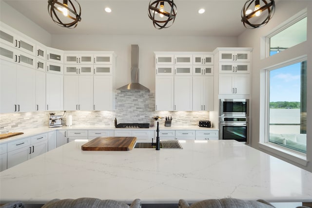 kitchen with decorative backsplash, a large island, a breakfast bar area, wall chimney range hood, and a sink