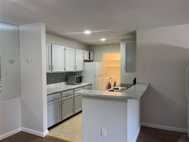 kitchen with light tile flooring, backsplash, white refrigerator, kitchen peninsula, and separate washer and dryer