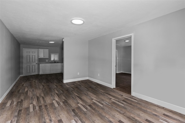 unfurnished living room featuring sink and dark wood-type flooring