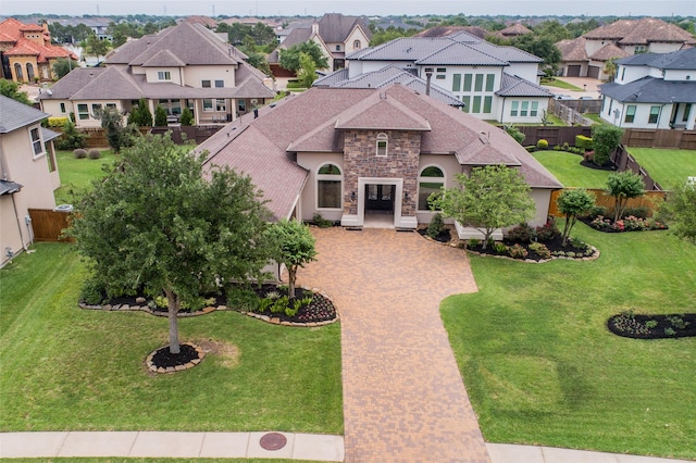 view of front of property with decorative driveway, roof with shingles, a front yard, a residential view, and stone siding