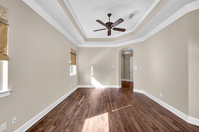 empty room with ceiling fan with notable chandelier, dark hardwood / wood-style flooring, crown molding, and a tray ceiling