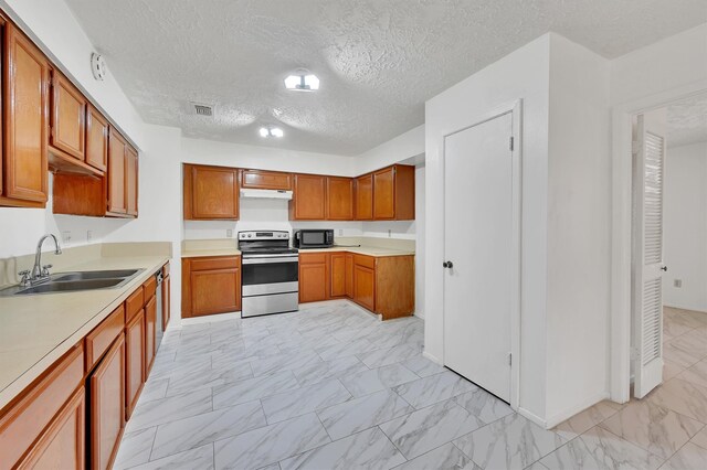 kitchen featuring sink, light tile floors, electric range, and a textured ceiling