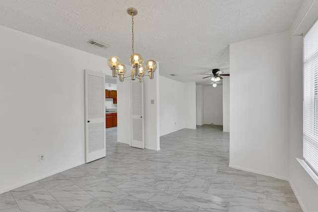 tiled empty room featuring ceiling fan with notable chandelier, a textured ceiling, and a healthy amount of sunlight