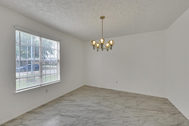 empty room featuring a textured ceiling, a healthy amount of sunlight, light tile floors, and an inviting chandelier