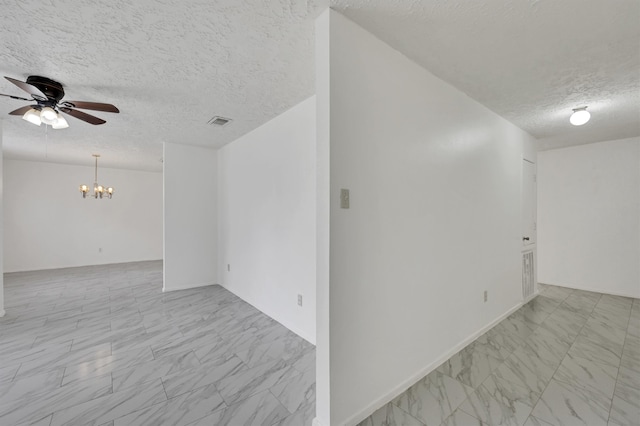 tiled empty room with ceiling fan with notable chandelier and a textured ceiling