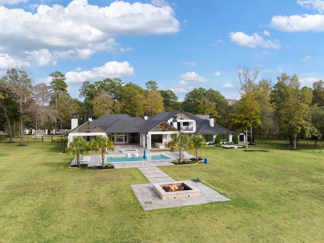 rear view of house with a fire pit, a yard, and a patio