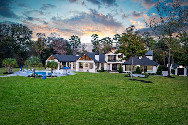 back house at dusk featuring a lawn