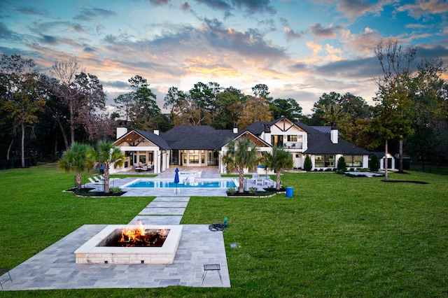 back house at dusk featuring a yard, an outdoor fire pit, and a patio