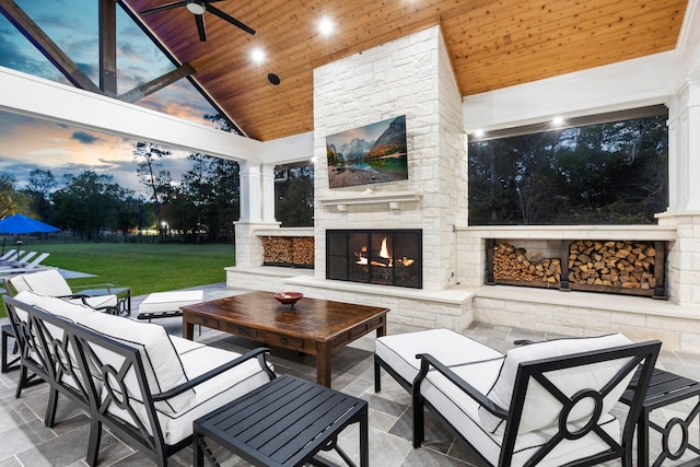 patio terrace at dusk with ceiling fan and an outdoor living space with a fireplace