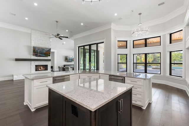 kitchen featuring kitchen peninsula, hanging light fixtures, light stone counters, and a fireplace