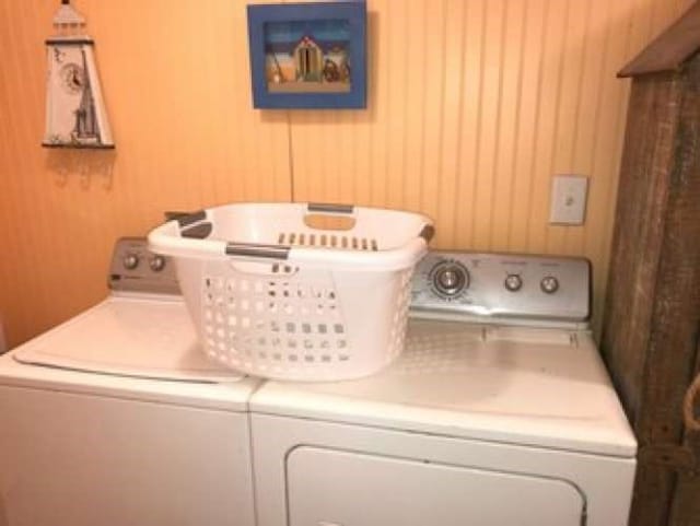 laundry area featuring wooden walls and washer and dryer