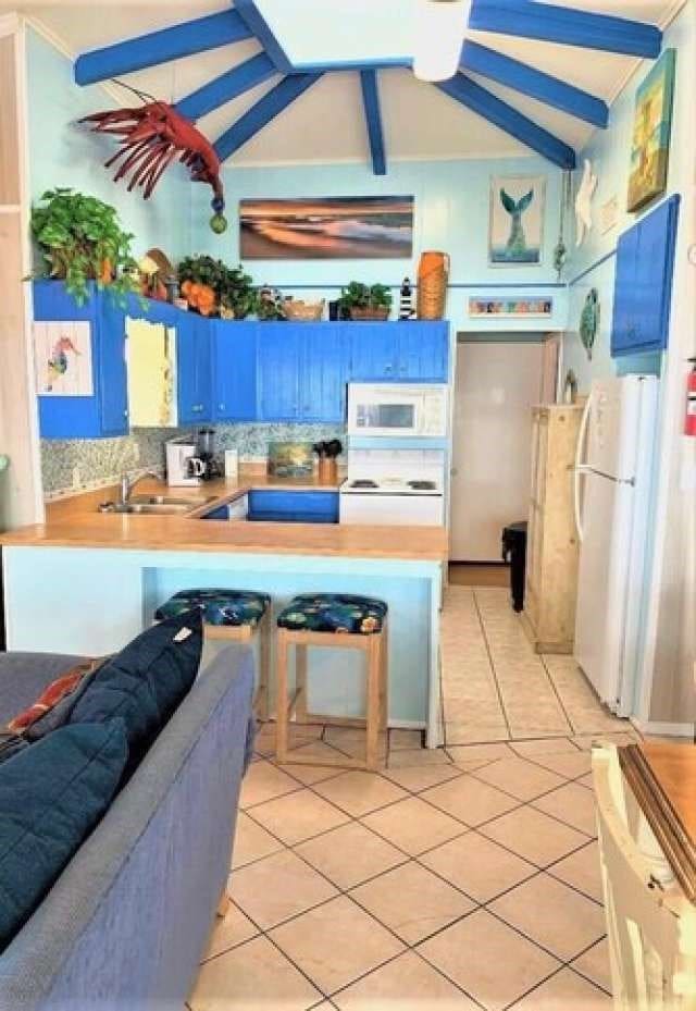 interior space featuring white appliances, lofted ceiling with beams, and light tile floors