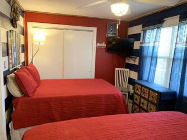 bedroom featuring a closet, ceiling fan, and multiple windows