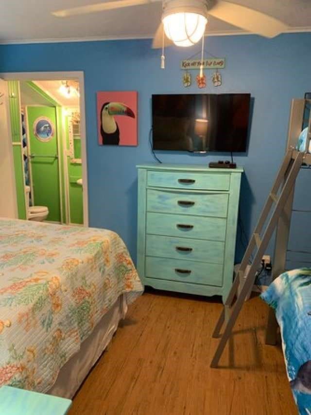 bedroom with ensuite bath, ceiling fan, and hardwood / wood-style flooring