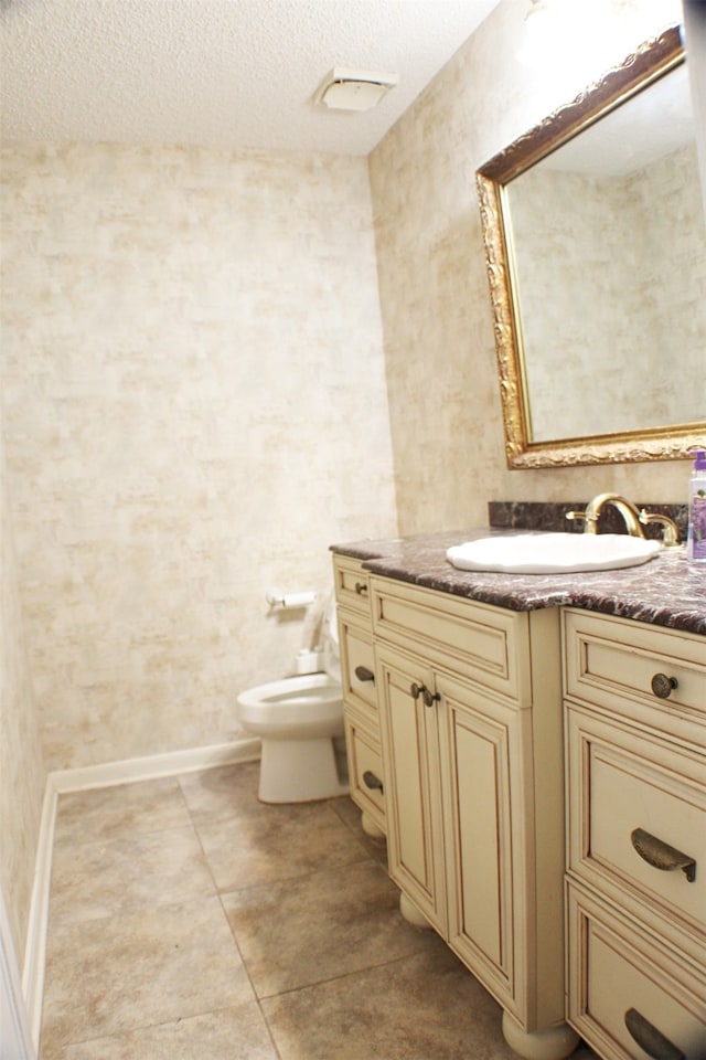 bathroom featuring vanity, toilet, tile floors, and a textured ceiling