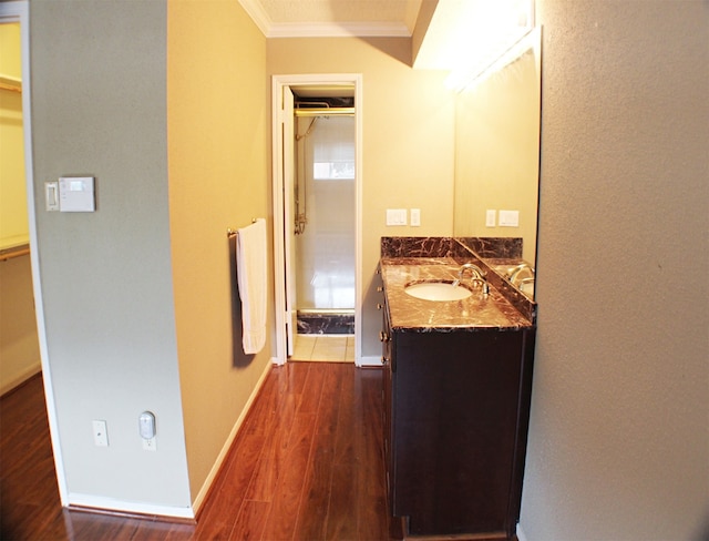 bathroom with crown molding, wood-type flooring, and vanity