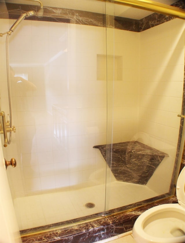 bathroom featuring an enclosed shower and toilet