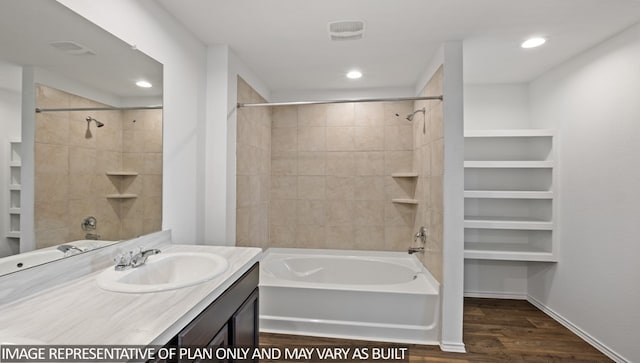 bathroom featuring wood-type flooring, vanity, and tiled shower / bath combo