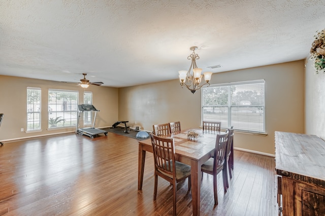 dining space featuring ceiling fan with notable chandelier, dark hardwood / wood-style flooring, and a textured ceiling