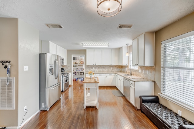 kitchen featuring stainless steel appliances, a center island, light hardwood / wood-style floors, and white cabinetry