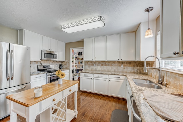 kitchen featuring stainless steel appliances, white cabinetry, sink, and light wood-type flooring