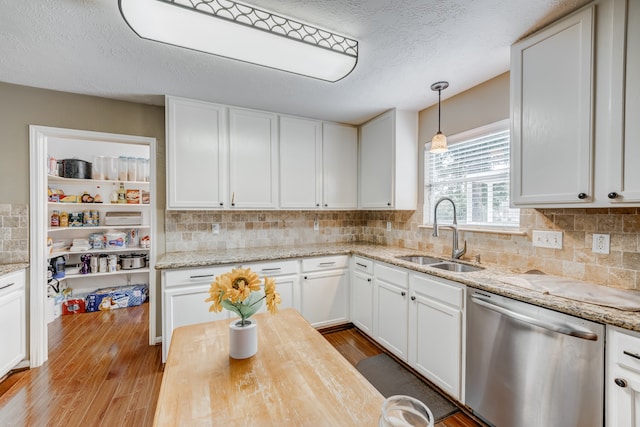 kitchen with white cabinets, light hardwood / wood-style flooring, sink, and stainless steel dishwasher