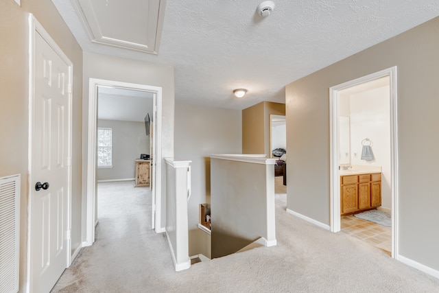 hallway featuring light colored carpet and a textured ceiling