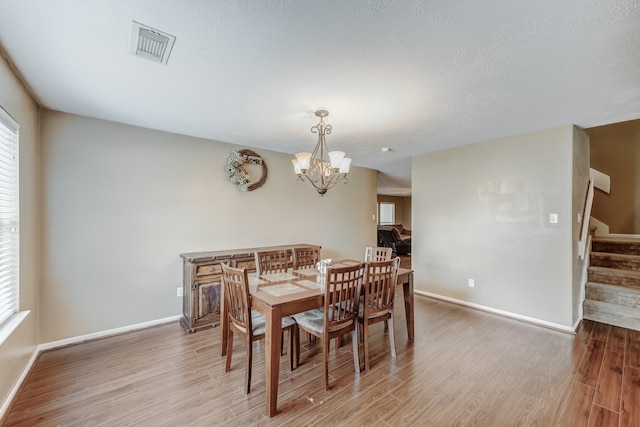 dining room with a textured ceiling, hardwood / wood-style floors, and a chandelier