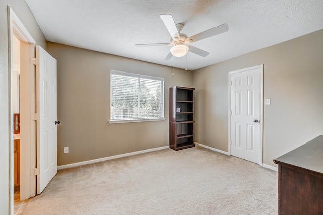 empty room with light colored carpet, ceiling fan, and a textured ceiling